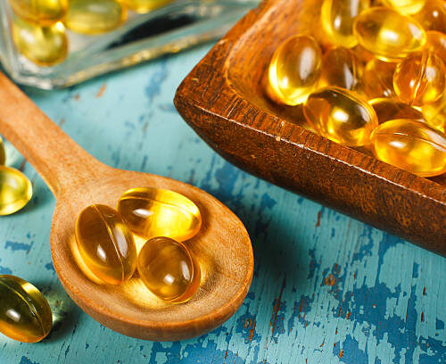 Cod Liver Oil Capsules on wooden spoon